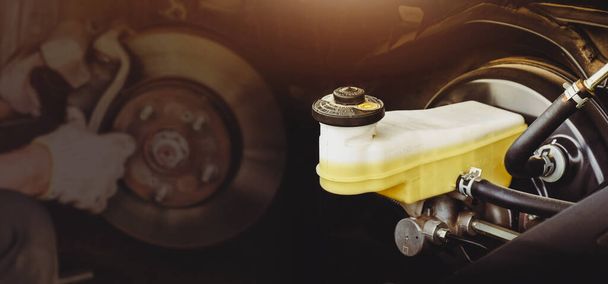 Auton jarrujärjestelmän jarrunesteen säiliö, jossa levyjarru korjaa kaksinkertaisen altistumisen hämärtyneenä taustalla - Valokuva, kuva