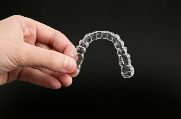 invisible aligners to correct dental misalignment on a black background - Foto, Imagen