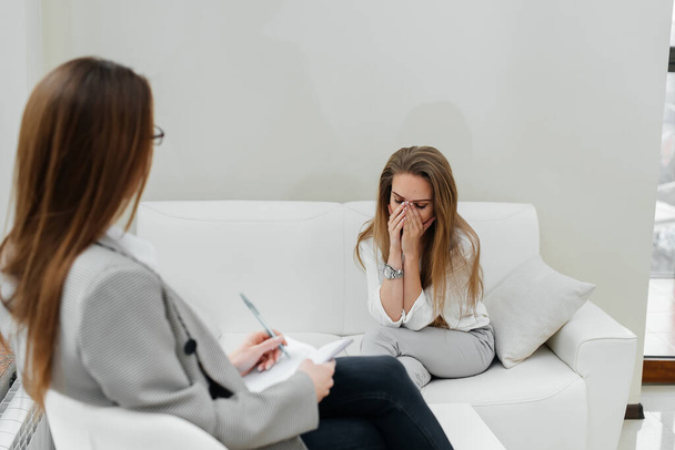 A young woman came to an appointment and consultation with a psychotherapist. Counseling and help during depression. Communication with a psychologist and a psychotherapist in the office. Psychological help. - 写真・画像
