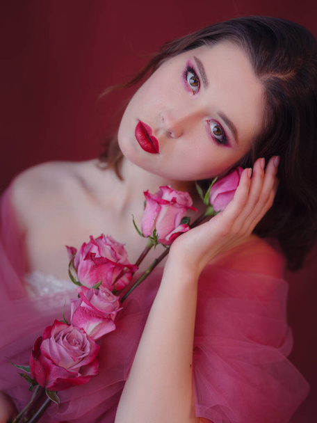 Attractive brunette asian woman with beautiful bouquet of flowers. Pretty woman with bright makeup. Art portrait with roses. Youth and skin care concept - 写真・画像