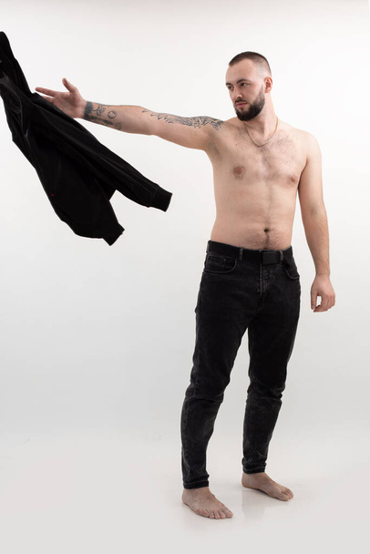 Confident and cool, handsome attractive man with beard and tattoo, shirtless and topless. Taking off throwing clothes - Fotó, kép