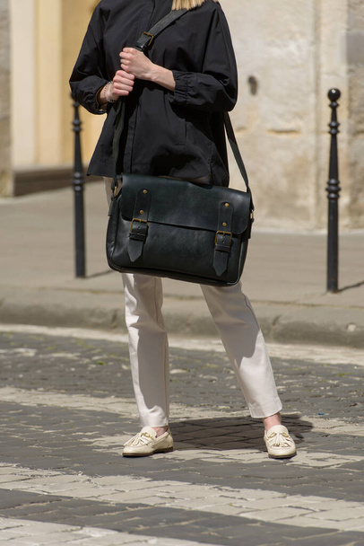 Part photo of a woman with a black leather briefcase with antique and retro look. Outdoors photo - Foto, immagini