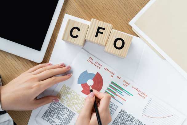 Dijital tabletin yanında tablolar ve Cfo harfli küplerle çalışan finans müdürünün üst görüntüsü  - Fotoğraf, Görsel