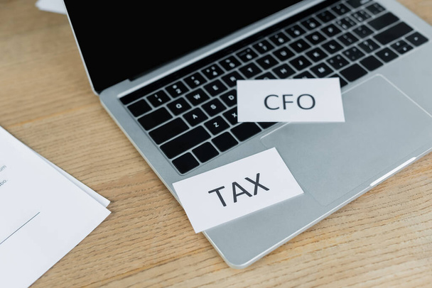 papers with tax and cfo lettering near laptop with blank screen - Fotografie, Obrázek