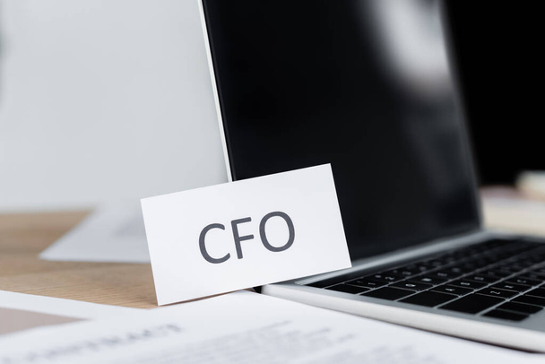 close up of paper cfo lettering near laptop with blank screen - Foto, imagen
