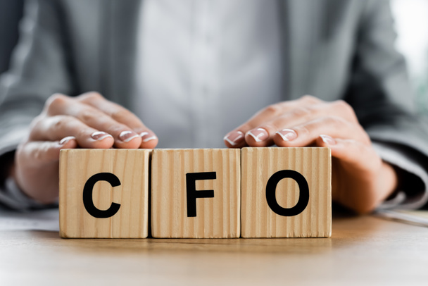 cropped view of woman holding wooden cubes with cfo lettering in office - Fotó, kép