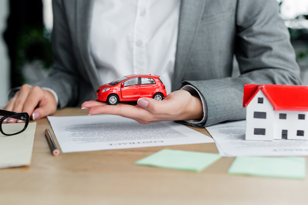 cropped view of tax inspector holding toy car near documents on table - Photo, Image