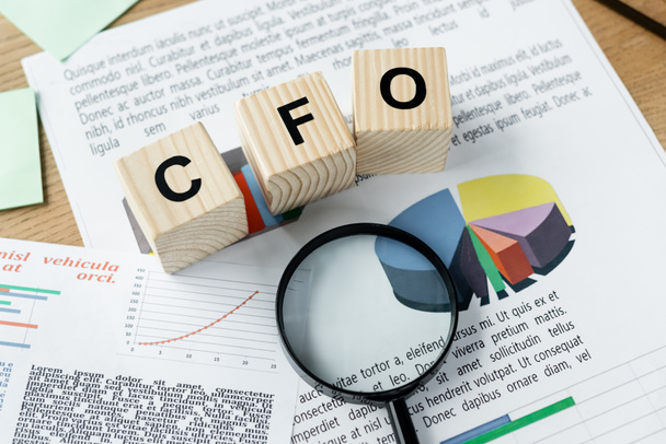 top view of magnifier on charts near cubes with cfo lettering - Foto, Bild