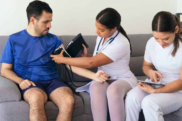 Enfermeiras examinando a pressão arterial de um homem. - Foto, Imagem