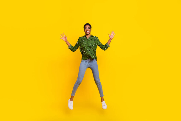 Photo of funky excited androgynous person dressed smart casual jumping high isolated yellow color background - Фото, изображение