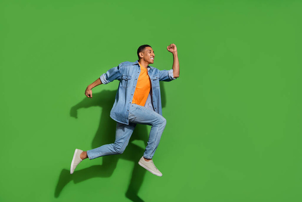 Full body photo of energetic active young handsome student age man running in air isolated on green color background - 写真・画像