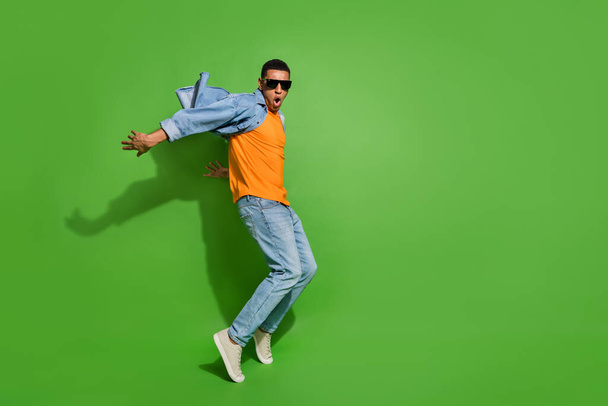 Full length profile side photo of crazy energetic active male have fun dancing isolated on green color background - Foto, imagen