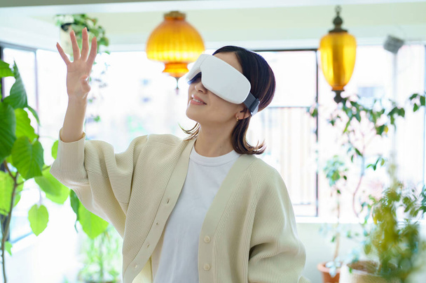 Eine Frau mit VR-Brille steht im Raum und tastet - Foto, Bild