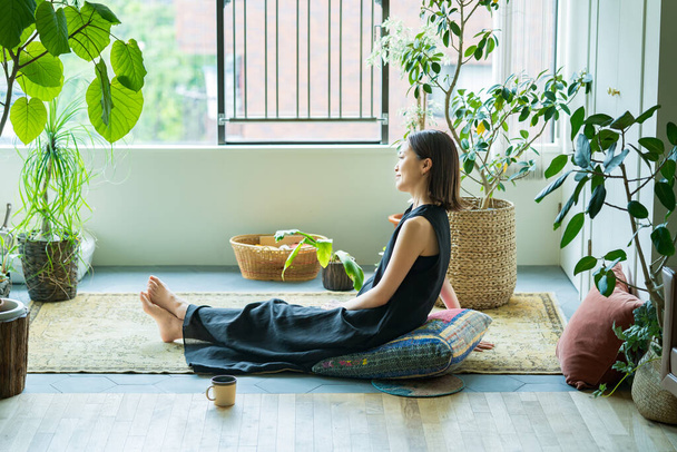 Жінка розслабляється в оточенні рослин листя в кімнаті
 - Фото, зображення