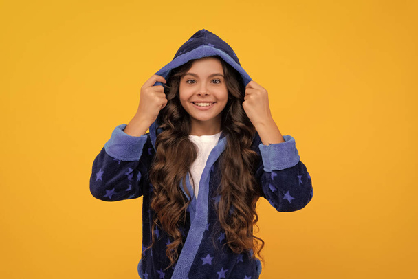 Glückliches Mädchen Kind lächelt im Kapuzenbademantel gelben Hintergrund, Homewear - Foto, Bild