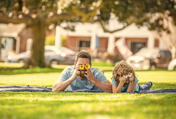 heureux père avec enfant se détendre ensemble sur l'herbe verte du parc jouer avec des fleurs, fête des pères - Photo, image