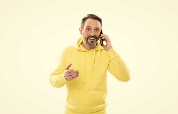 smiling handsome mature man in hoody speaking on phone isolated on white, conversation. - Fotografie, Obrázek