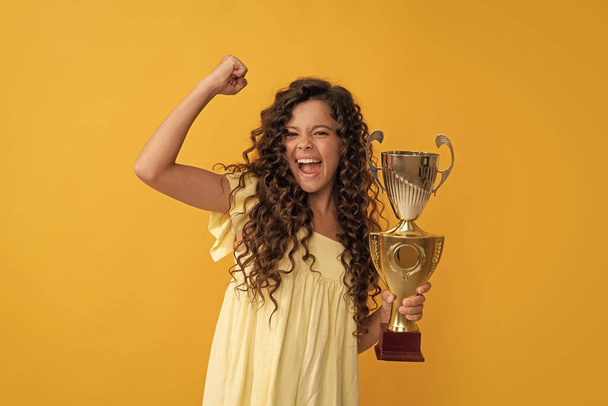 ハッピーティーンの女の子は黄金のカップを保持します。功績賞。成功と勝利を祝う. - 写真・画像