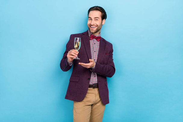 Photo of young cheerful guy present wine promo recommend waiter suggest isolated over blue color background - Fotografie, Obrázek