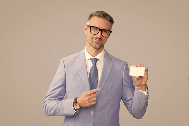 smiling mature man in glasses pointing finger on credit card and thumb up, copy space, call me - Photo, Image
