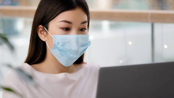 Asian student Korean business woman in medical face mask freelancer writer journalist typing working laptop using free Wi-Fi studying with computer app e-learning distant education pandemic e-commerce - Foto, Bild