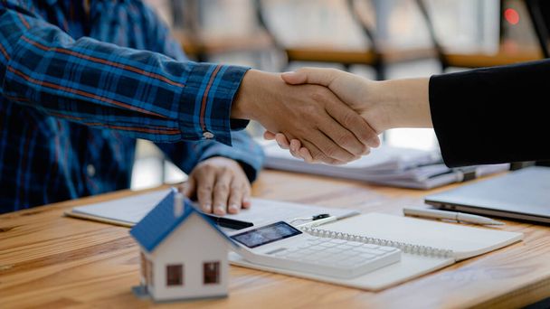 The salesperson of the housing estate in the project and the customer shake hands after successfully signing the contract. Concept of selling housing estates and real estate. - Fotoğraf, Görsel
