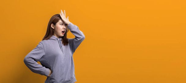 Portrait of beautiful Asian woman gesturing surprise on isolated background, portrait concept used for advertisement and signage, isolated over yellow background, copy space. - Foto, Imagem