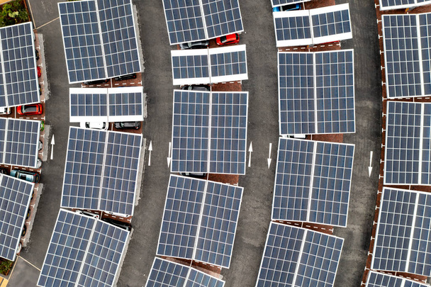 Aerial view above innovative solar panels located on a car parking lot rooftops making good use of small space in a city - Фото, изображение