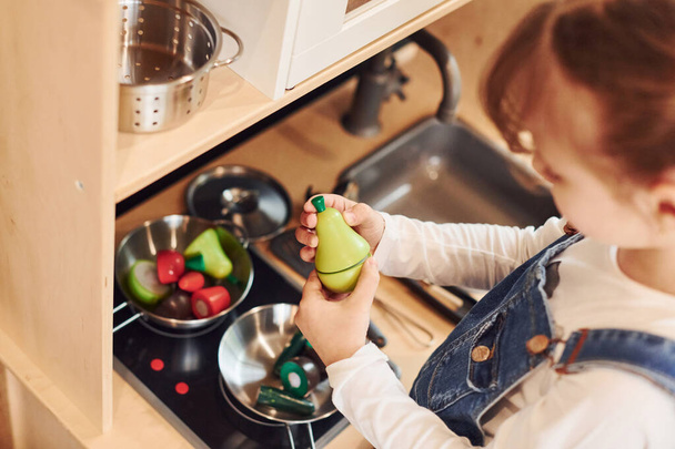 Little girl in casual clothes have fun by playing with toys on the kitchen. - Fotografie, Obrázek