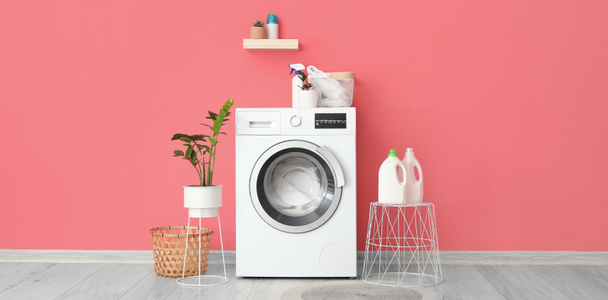 Інтер'єр стильної пральної кімнати з сучасною пральною машиною біля рожевої стіни
 - Фото, зображення
