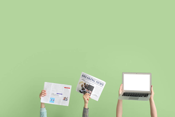People with newspapers and laptop on green background - Foto, afbeelding