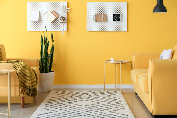 Nappali kanapéval, fotellel és szegéllyel a színes fal mellett - Fotó, kép