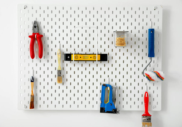 Pegboard με διάφορα σύγχρονα εργαλεία στον ελαφρύ τοίχο - Φωτογραφία, εικόνα