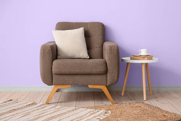 Mukava nojatuoli ja pöytä kupin kahvia lähellä violetti seinä huoneessa - Valokuva, kuva
