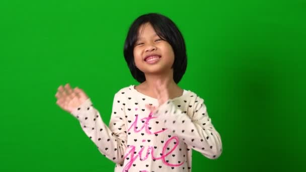 Portret van gelukkige Aziatische meisje beweging naar een camera op groen scherm achtergrond, een kind op zoek naar camera. kleuter dromen vullen met energie gevoel gezond en goed concept - Video
