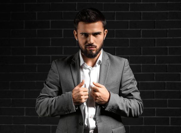 Bearded businessman wearing stylish suit on dark background - Foto, imagen