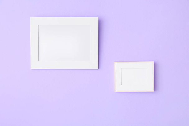 Blank photo frames hanging on lilac wall - Zdjęcie, obraz
