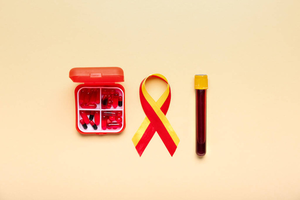 Awareness ribbon with pills and blood sample on beige background. Hepatitis concept - Photo, image