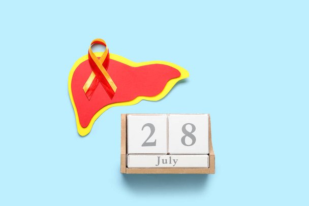 Awareness ribbon, paper liver and cube calendar with date 28 JULY on blue background. World Hepatitis Day - Photo, image