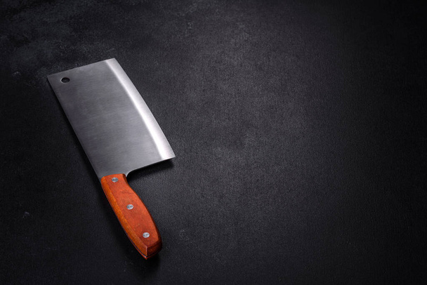Un'ascia per tagliare la carne su uno sfondo di cemento scuro. Preparare la carne per una deliziosa bistecca - Foto, immagini