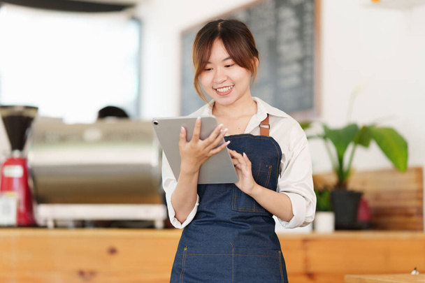 Retrato del dueño de la cafetería barista asiática con tableta para comprobar el orden. Empresario PYME vendedor concepto de negocio. - Foto, imagen