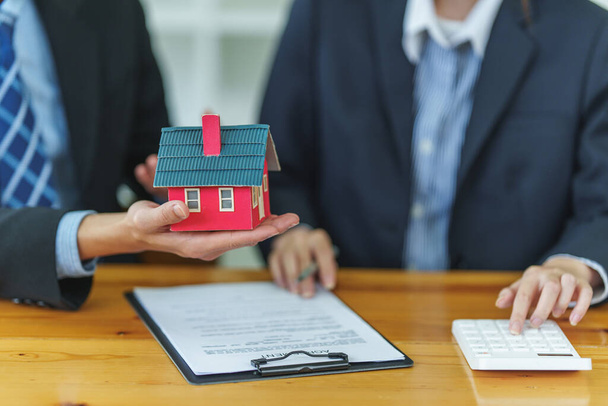 Close up Business woman or agent checking agreement contract before giving house for buying house. Bank manager and real estate concept. - Photo, image