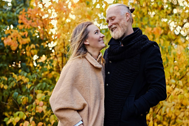 Couple of elderly man and young woman in autum - Foto, imagen