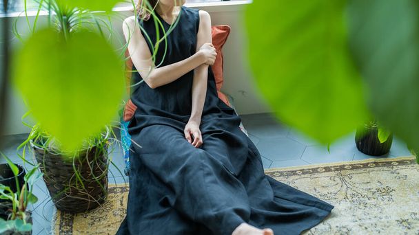 Uma mulher relaxante cercada por plantas de folhagem no quarto - Foto, Imagem