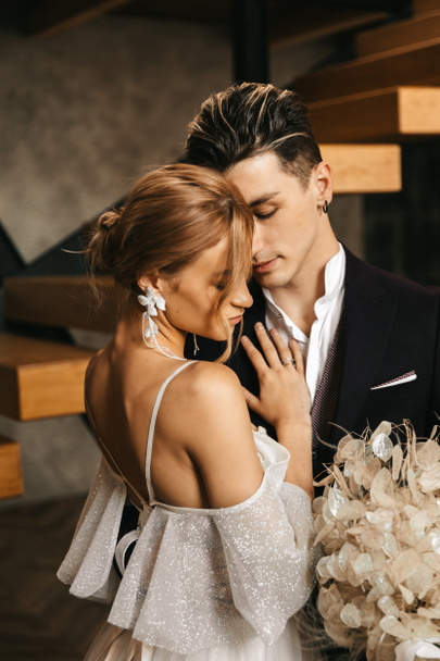 Les jeunes mariés s'embrassent magnifiquement et tendrement dans le studio du loft. Photo de haute qualité - Photo, image