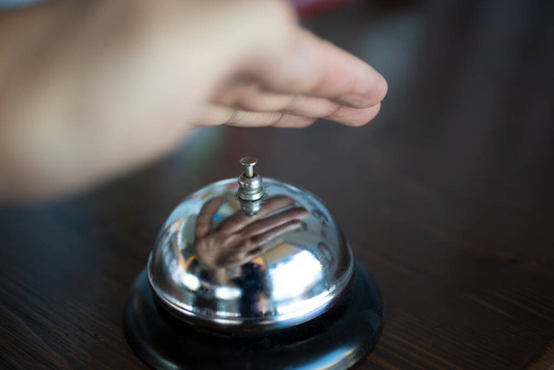 Una vista de una mano flotando sobre una campana de servicio, listo para pedir servicio. - Foto, Imagen