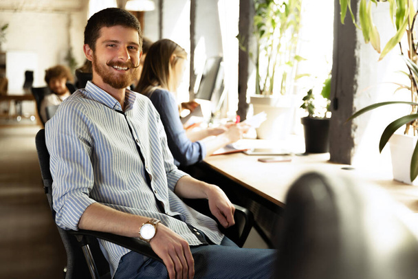 Senior developer. Happy man looking at camera and smilling. Work in modern loft style office using devices and gadgets during job processing. - Foto, Bild