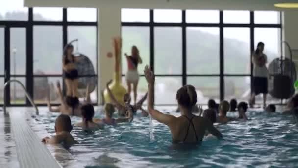 κορίτσια, παιδιά και γυναίκες κάνουν aqua fitness στην εσωτερική πισίνα - Πλάνα, βίντεο