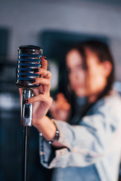 Close up view of microphone. Young beautiful female performer rehearsing in a recording studio. - Fotoğraf, Görsel