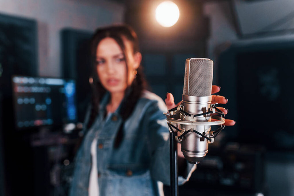 Close up view of microphone. Young beautiful female performer rehearsing in a recording studio. - Φωτογραφία, εικόνα